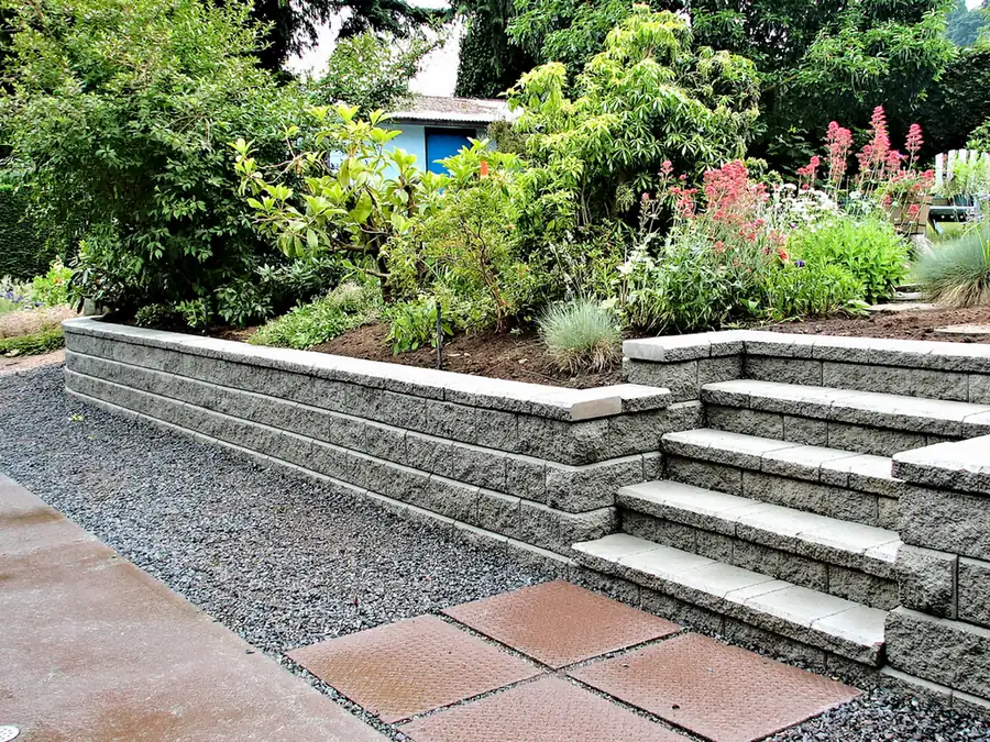 Block retaining wall with steps and planted terraces beside a gravel path in Parker, CO