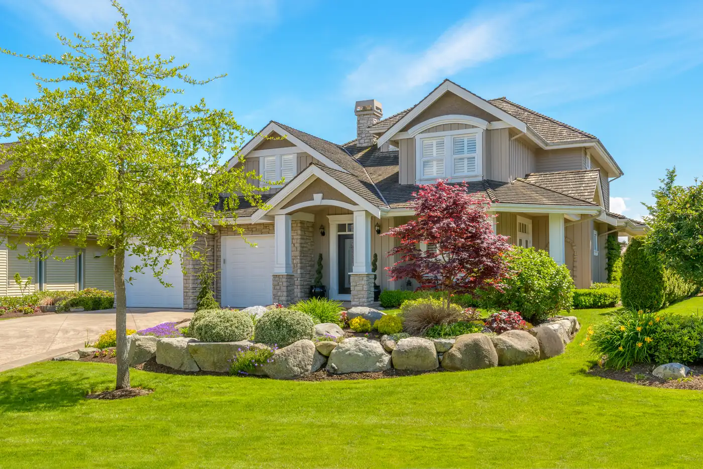 Boulder-bordered front yard Front yard with a boulder border, Japanese maple and evergreen shrubs at a two-story home in Parker, CO