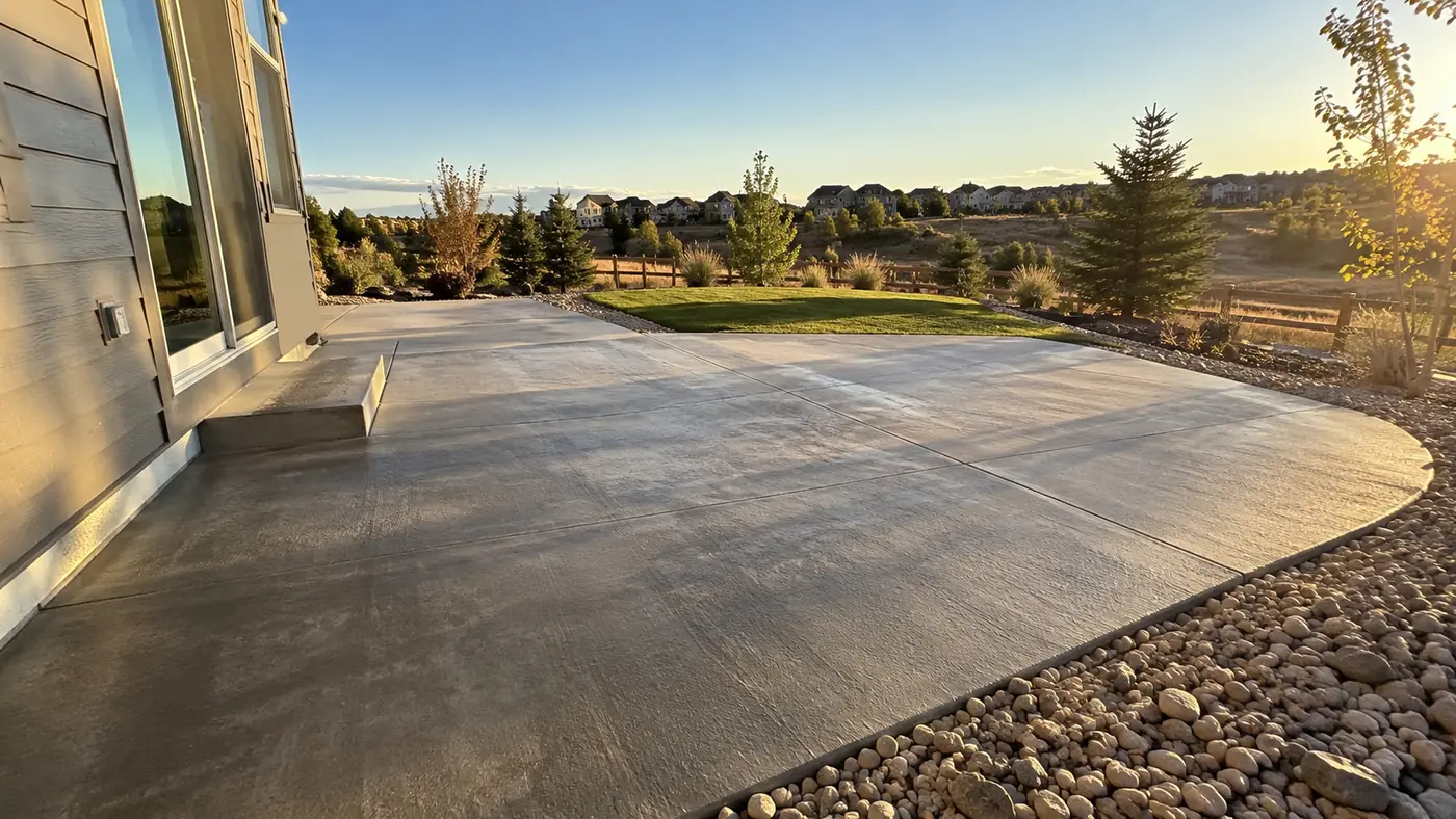Concrete patio at sunrise Concept rendering: broom-finish concrete patio with a river rock border at sunrise on the plains in Parker, CO
