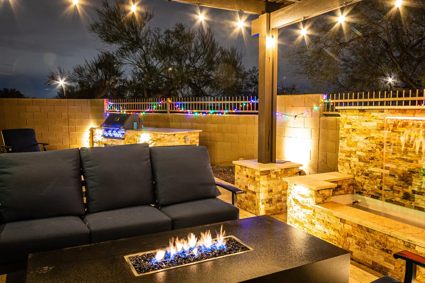 Outdoor living at night Outdoor living area at night with a fire table, sectional, stone bar and string lights in Parker, CO