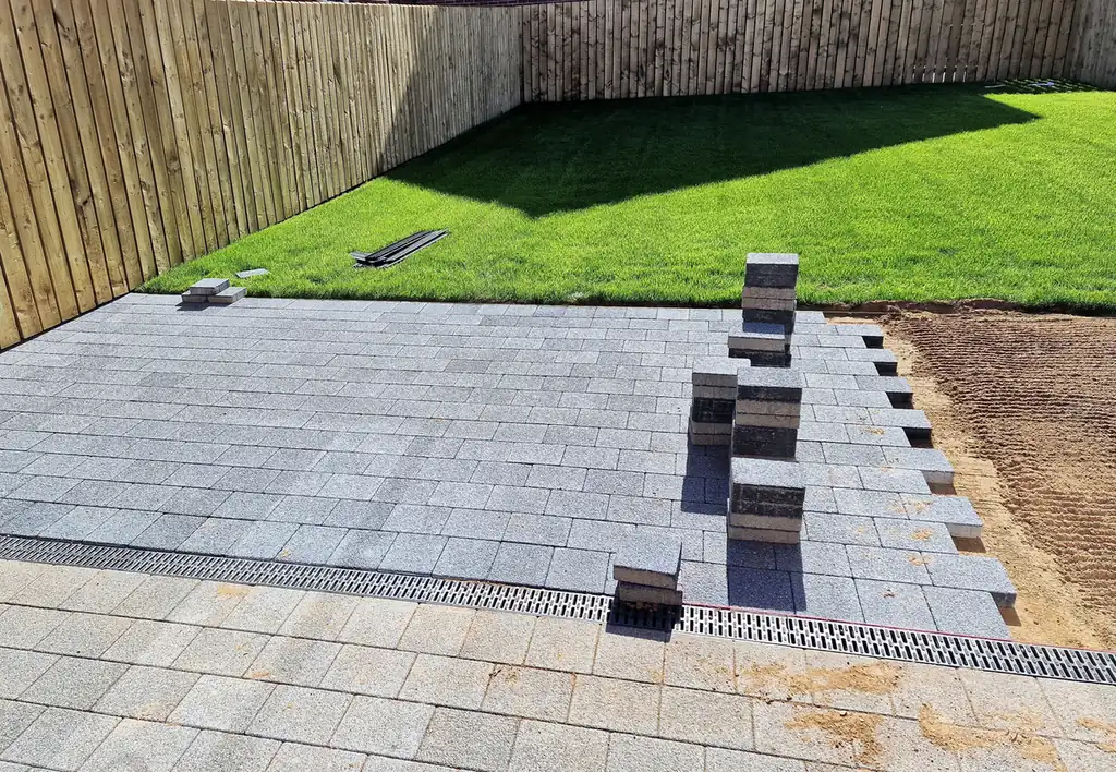 Paver patio with new sod Gray paver patio with a channel drain and fresh sod along a cedar fence in Aurora, near Parker, CO
