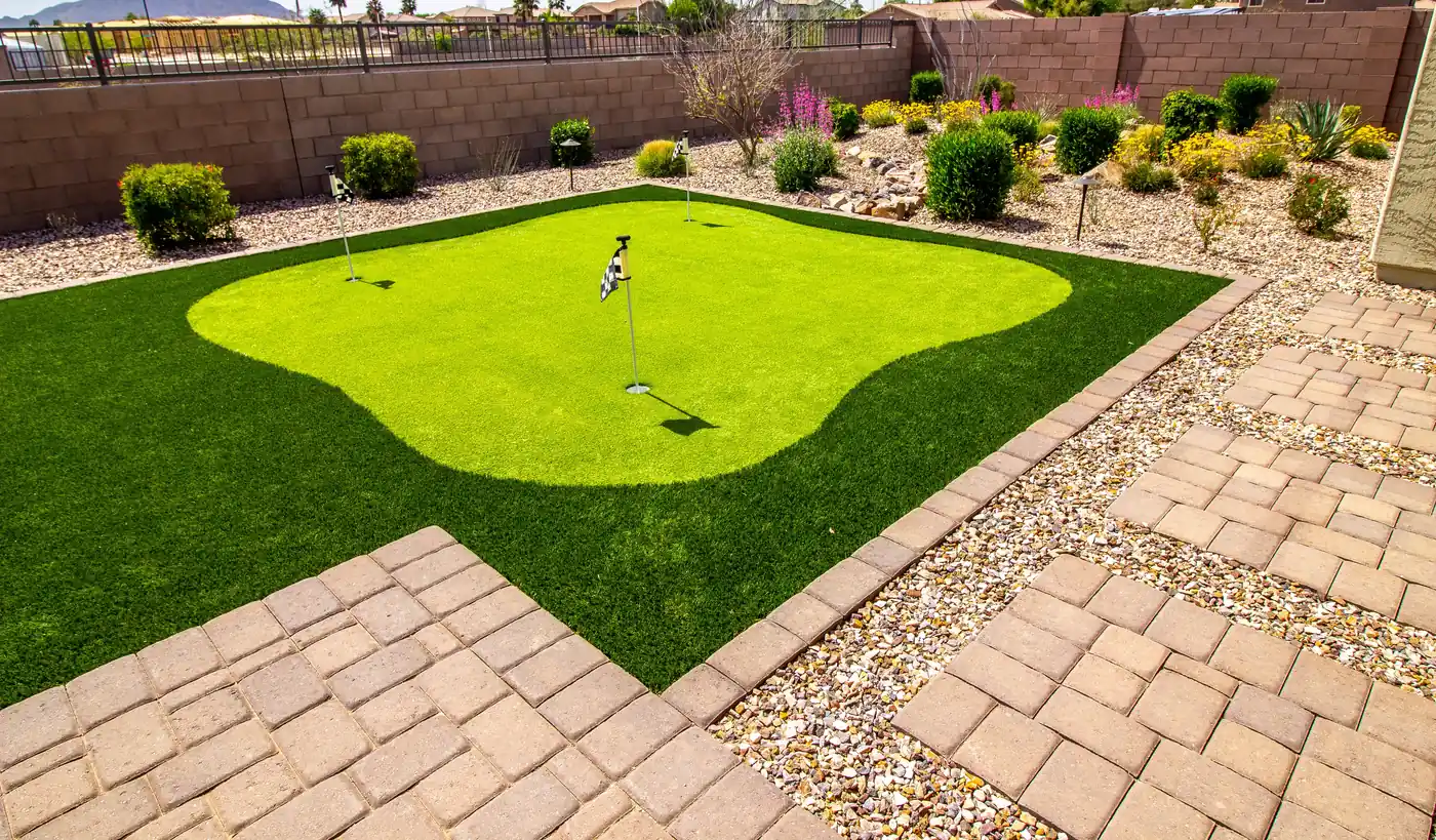 Synthetic putting green surrounded by xeriscape rock beds and a paver patio in Aurora, near Parker, CO