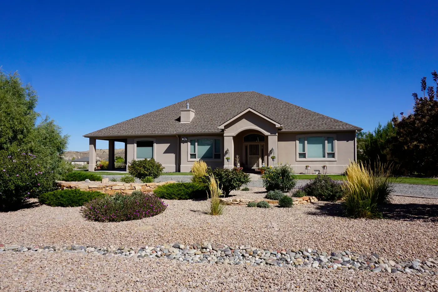 Xeriscape in Pradera Xeriscaped front yard of gravel, boulders and grasses at a stucco ranch home in Pradera, Parker, CO